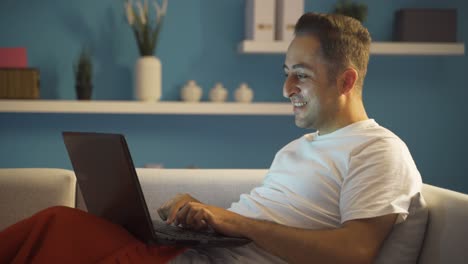 Hombre-Feliz-Usando-Una-Computadora-Portátil-Acostada.